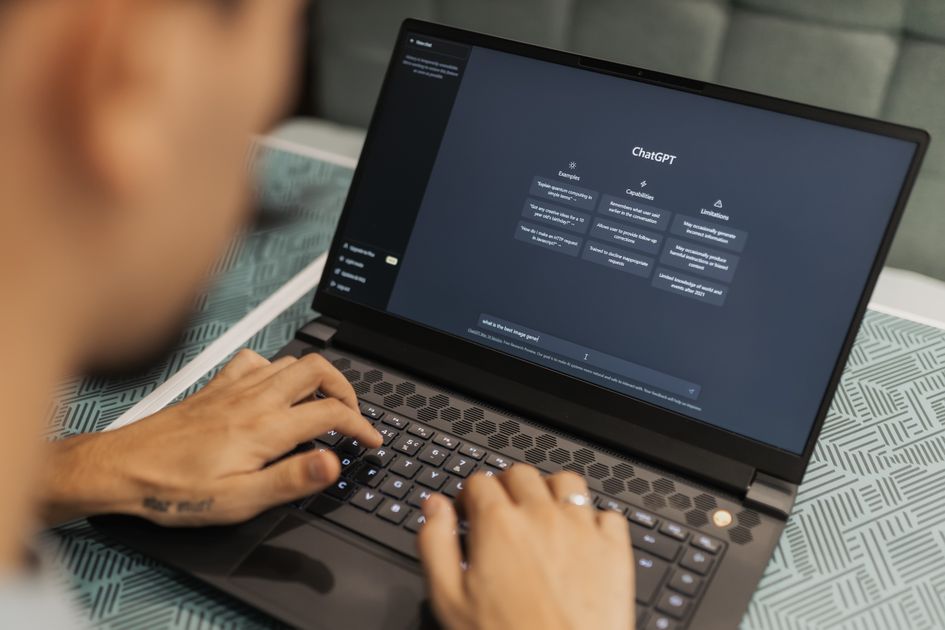 A person types on a laptop showing an AI chat conversation on screen.