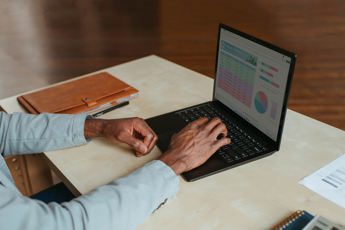 A person types on a laptop at a desk while composing a prompt for an AI assistant.